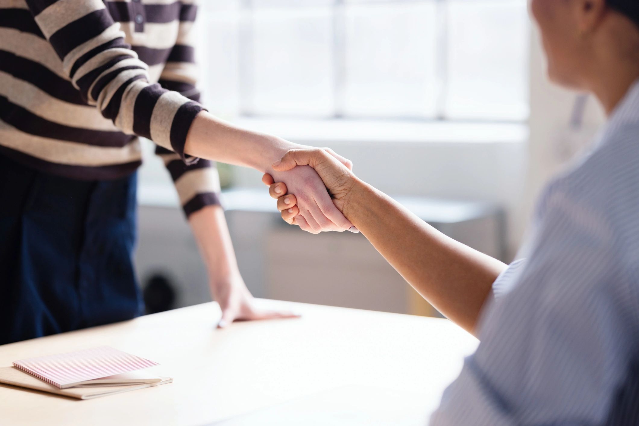 Business partnership handshake across a meeting table